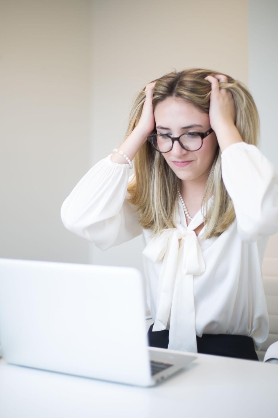 Free Image of Woman frustrated at laptop in office pulling her hair upset. 
