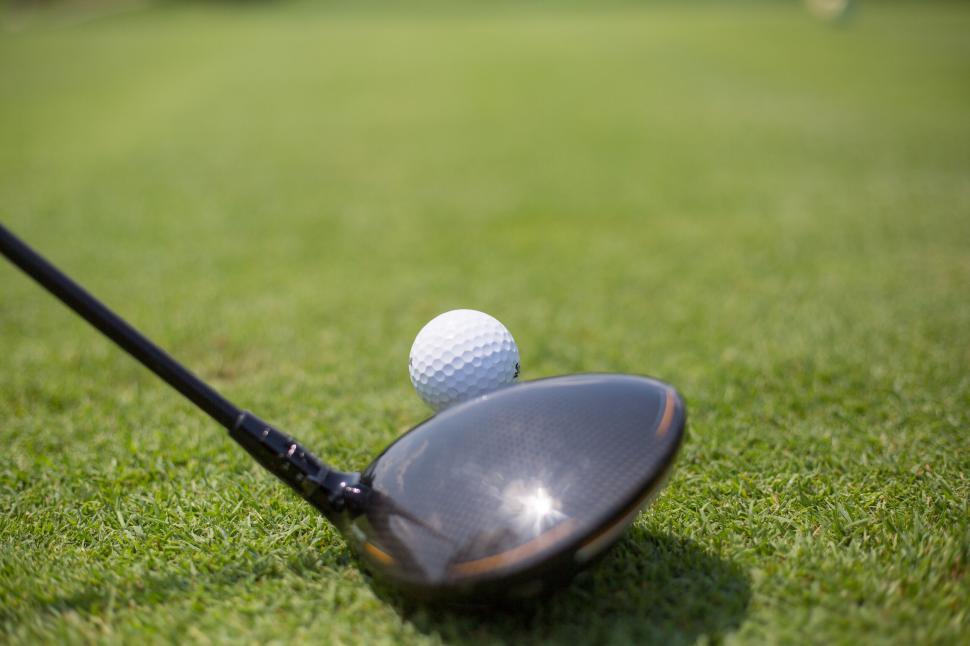 Free Image of Close-up of a golf club about to strike a golf ball on green turf 