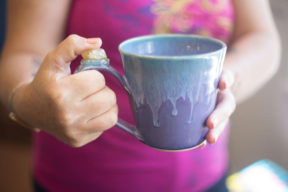 Free Image of Close-up of a blue ceramic mug being held in hands, vibrant detail 