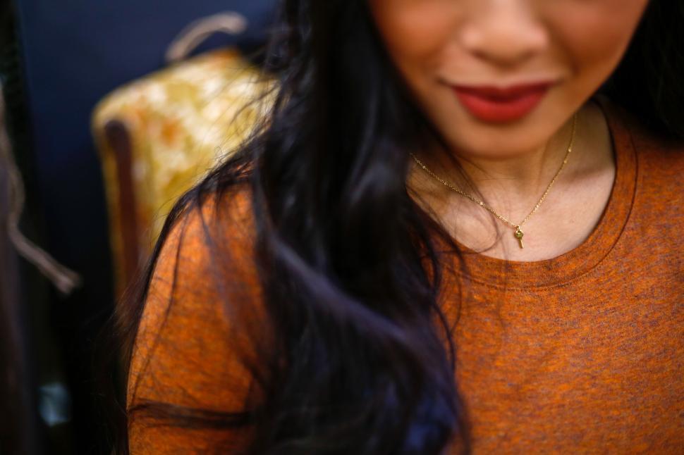 Free Image of Woman wearing a necklace, sitting on a patterned chair, upper view 