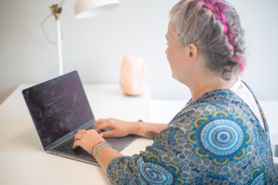Free Image of Person typing on laptop with braided hair and colorful shirt. 