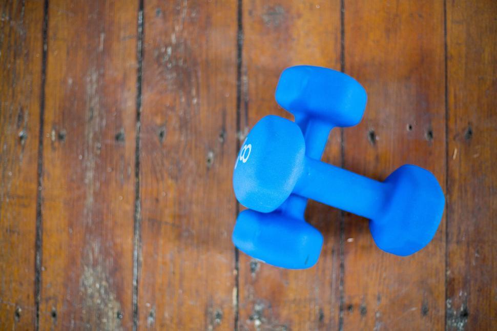Free Image of Blue dumbbells resting on wooden floor for fitness exercise. 