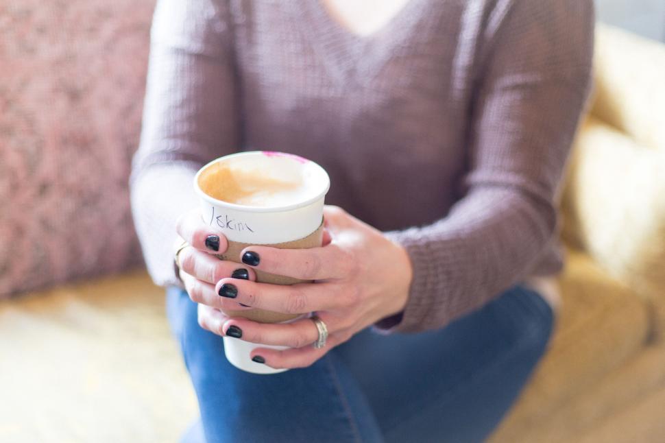 Free Image of Person holding a takeaway coffee cup in a casual setting. 