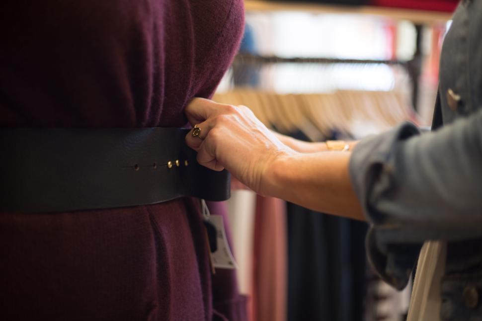 Free Image of Person adjusting belt on clothing mannequin in boutique. 