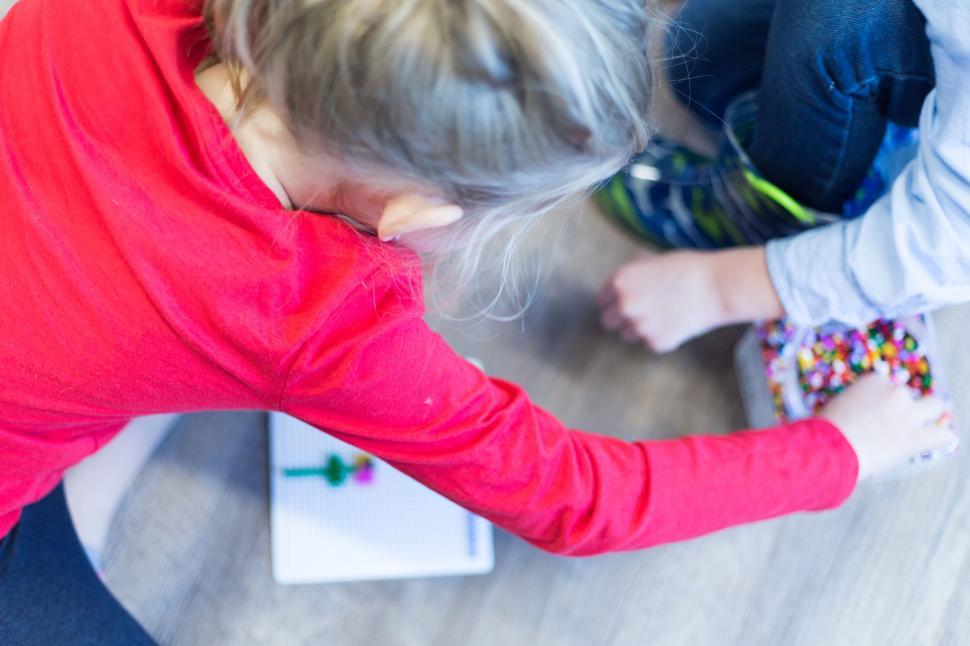 Free Image of Children playing with beads and crafting on the floor together 