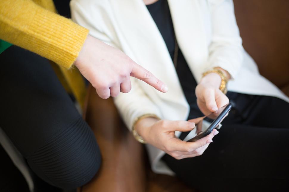 Free Image of Close-up of person using smartphone while sitting on a sofa 