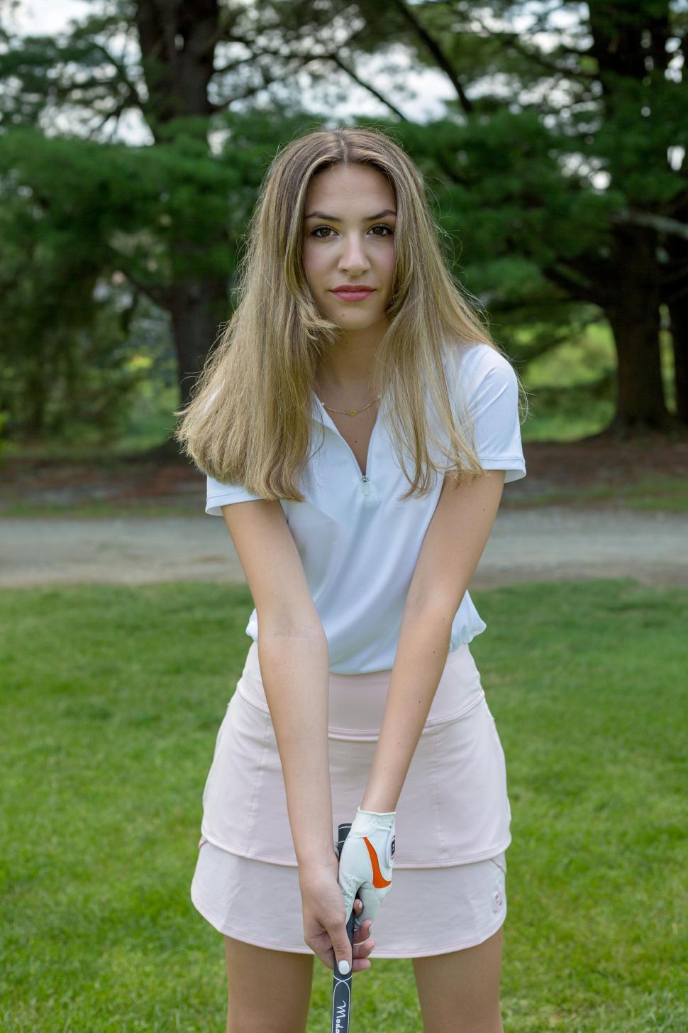 Free Image of Woman golfer preparing to swing on a lush golf course 