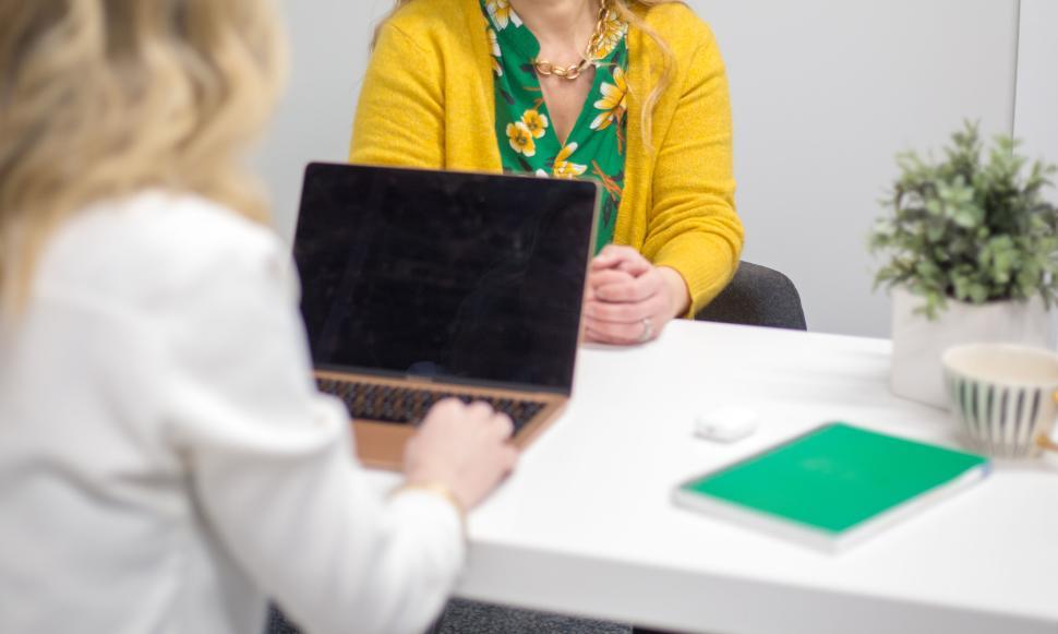 Free Image of Two women having a meeting at a white desk with laptop 