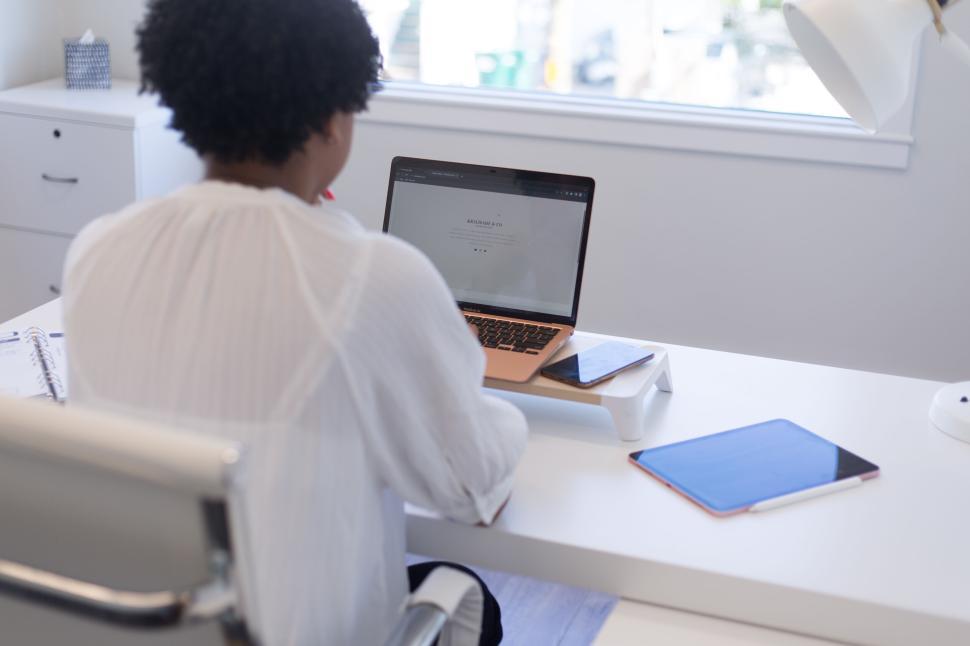 Free Image of Person working on a laptop at a white desk in an office 