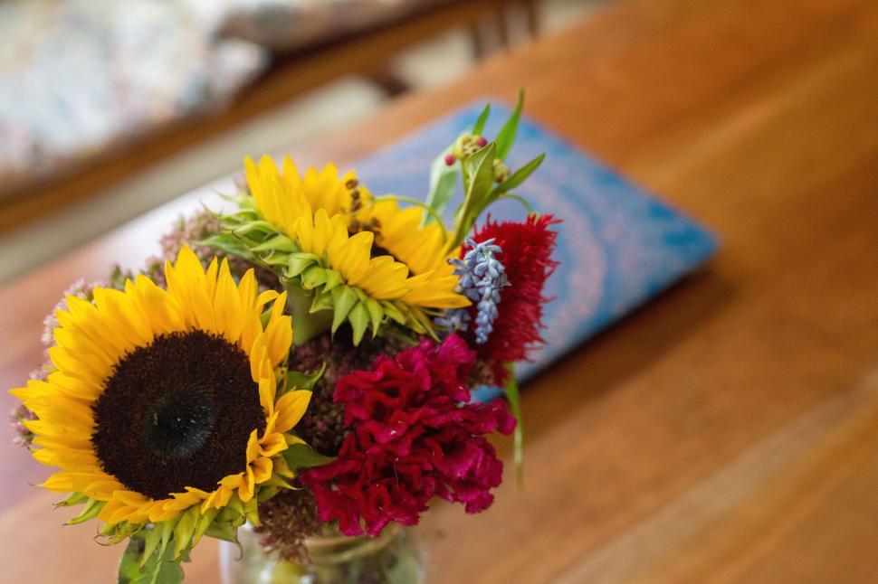Free Image of Sunflowers and red flowers in a vase on a wooden table 