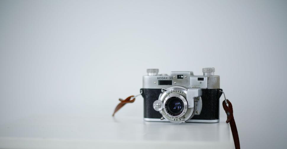 Free Image of Vintage Kodak 35mm camera on white tabletop surface with plain background. 