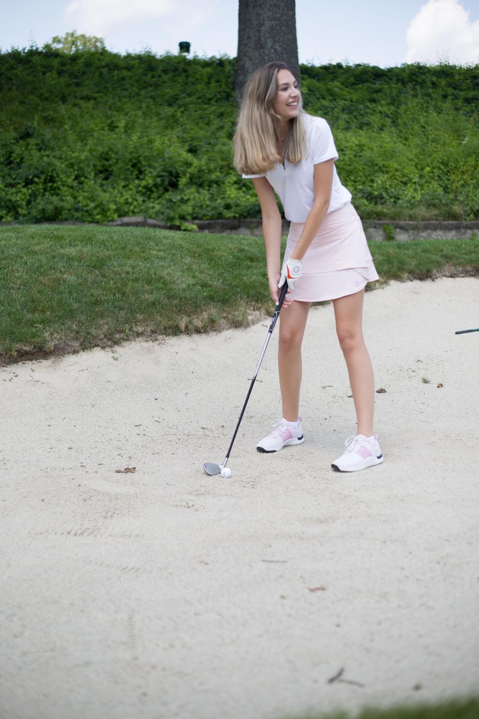 Free Image of Woman golfer in a sand bunker preparing for her shot 