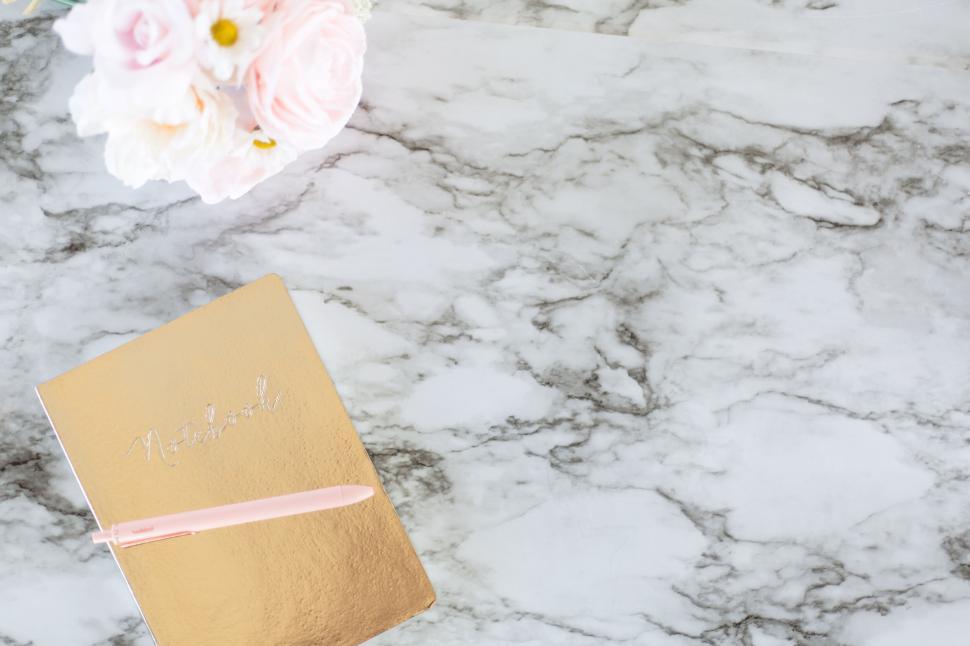 Free Image of Golden notebook on a marble table with soft pink flower bouquet 