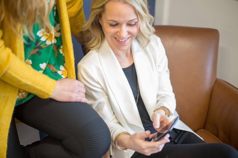 Free Image of Two women looking at a smartphone and smiling together 