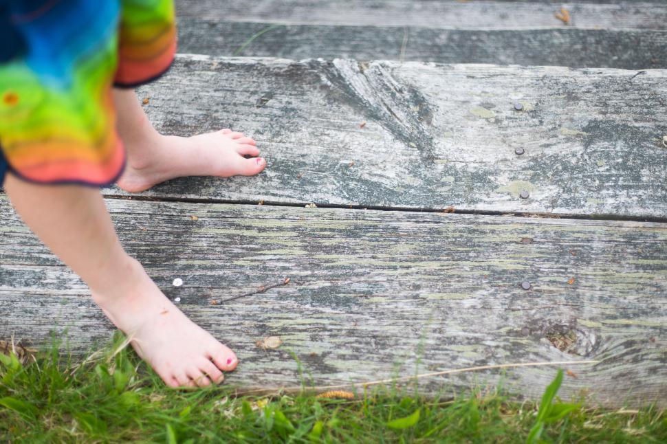 Free Image of Child standing barefoot on weathered wooden steps, outdoors, close-up. 