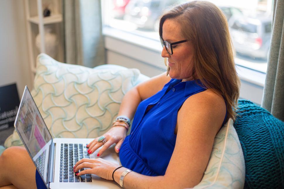 Free Image of Woman typing on her laptop while relaxing on comfortable couch 