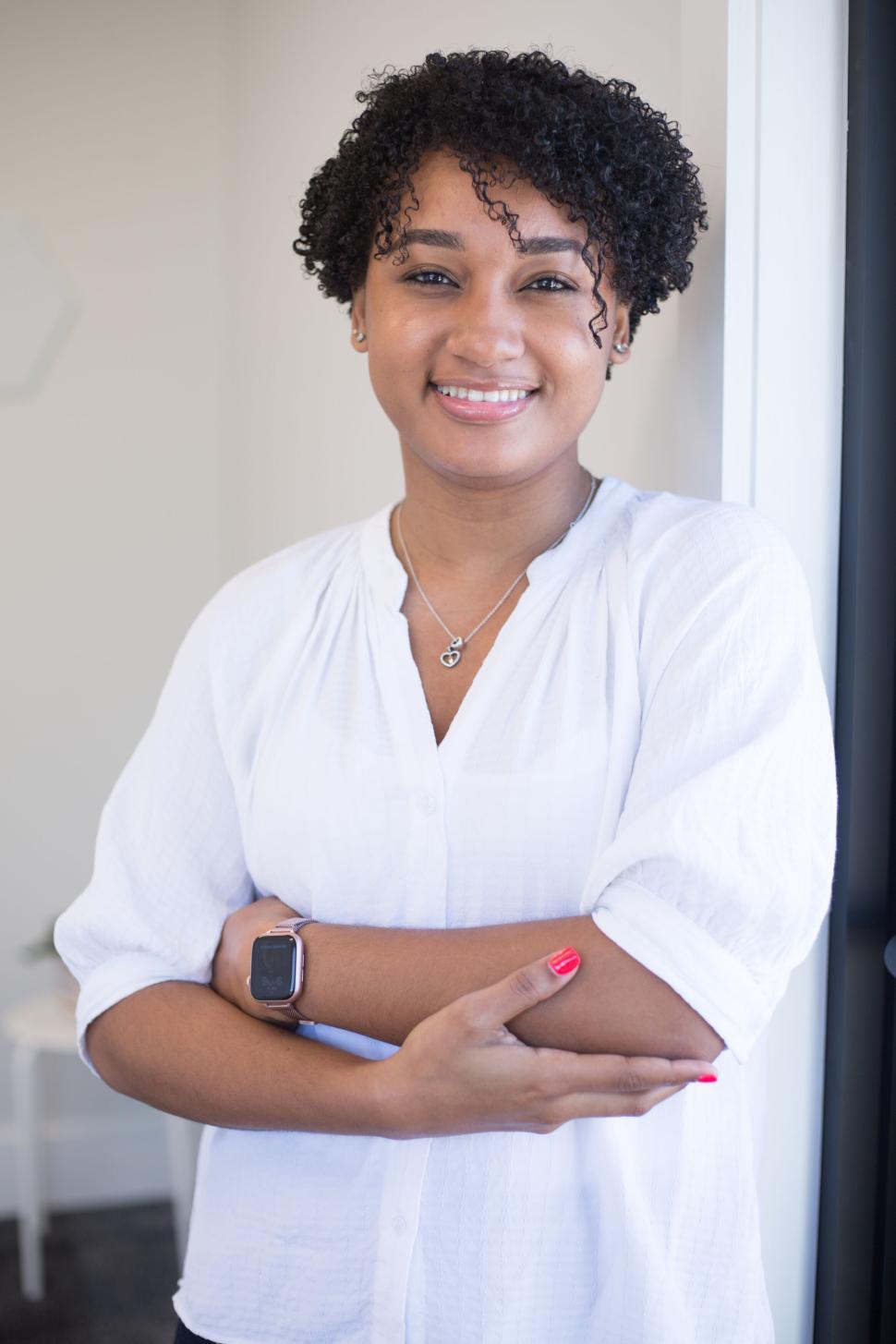 Free Image of Woman in white blouse leaning and smiling with arms crossed 