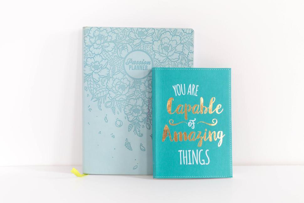 Free Image of Two teal notebooks on a white surface with motivational quotes 