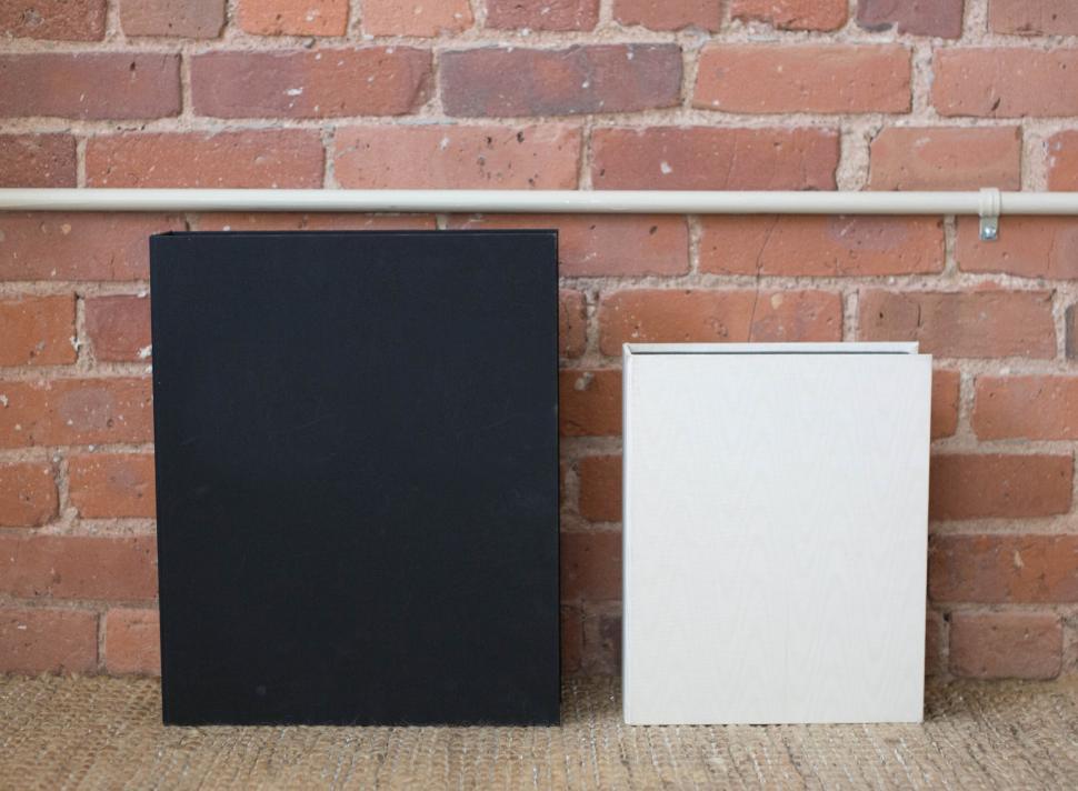 Free Image of Two contrasting books against brick wall, symbolizing knowledge diversity. 