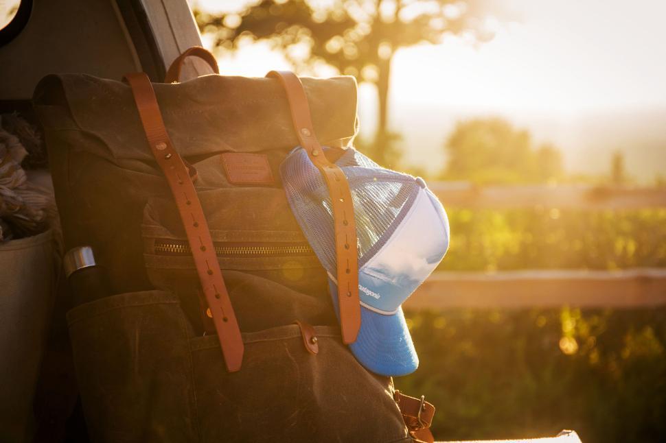 Free Image of Backpack with blue hat at the back of a vehicle during sunset 