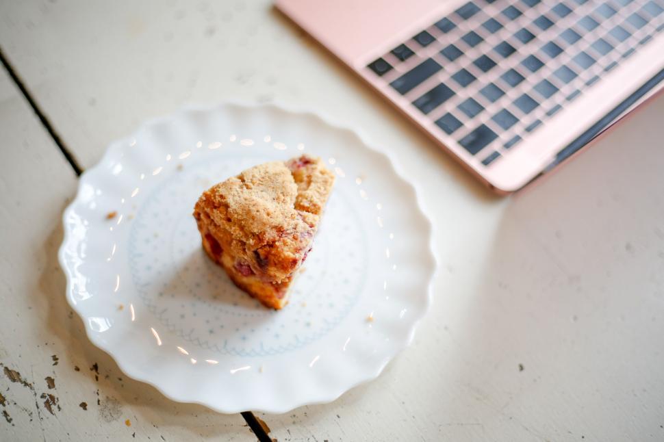 Free Image of Piece of crumb cake on delicate plate beside a modern laptop 