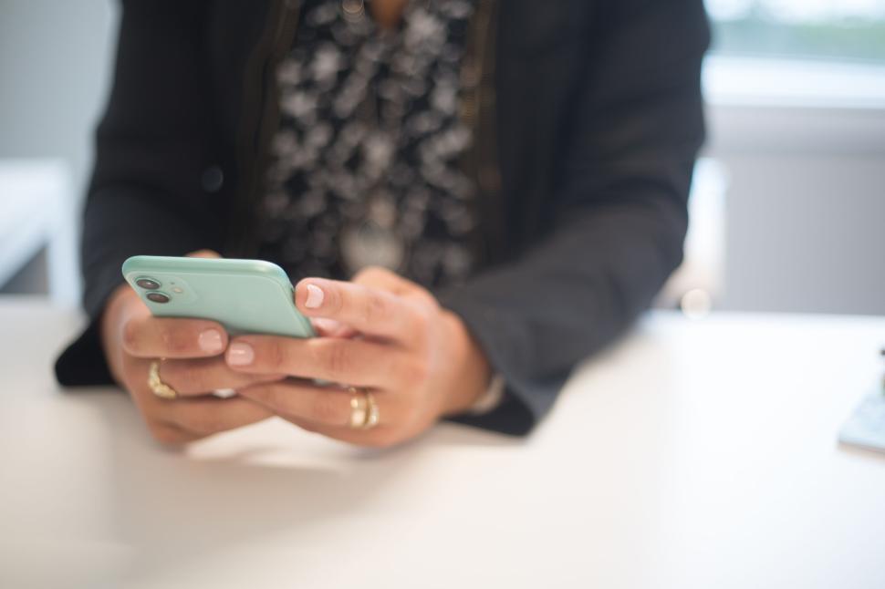 Free Image of Person holding teal phone with both hands, wearing multiple rings. 