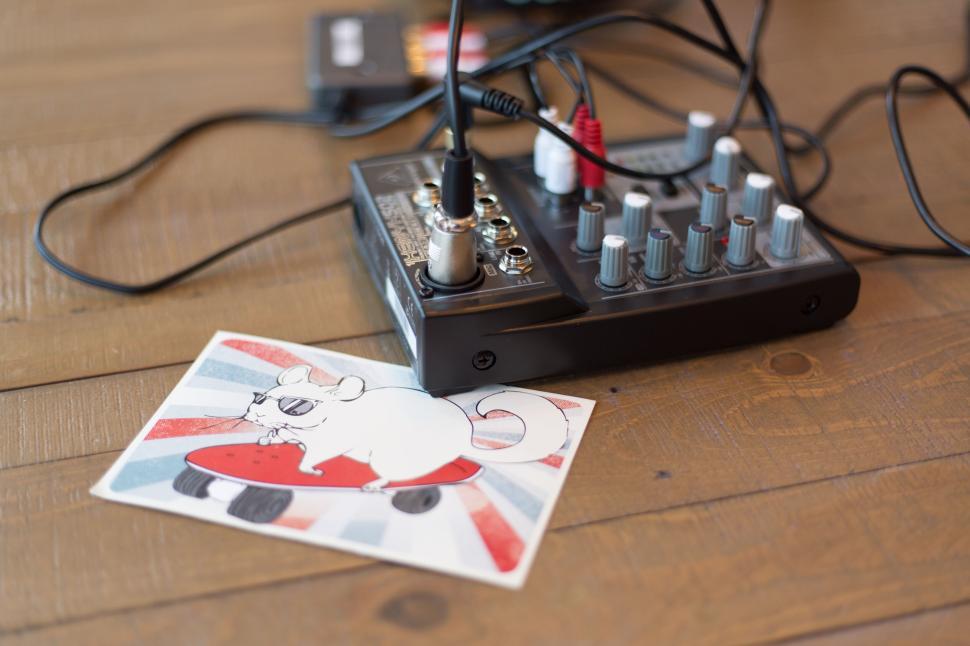 Free Image of Audio mixer on wooden table with cartoon mouse on skateboard sticker. 