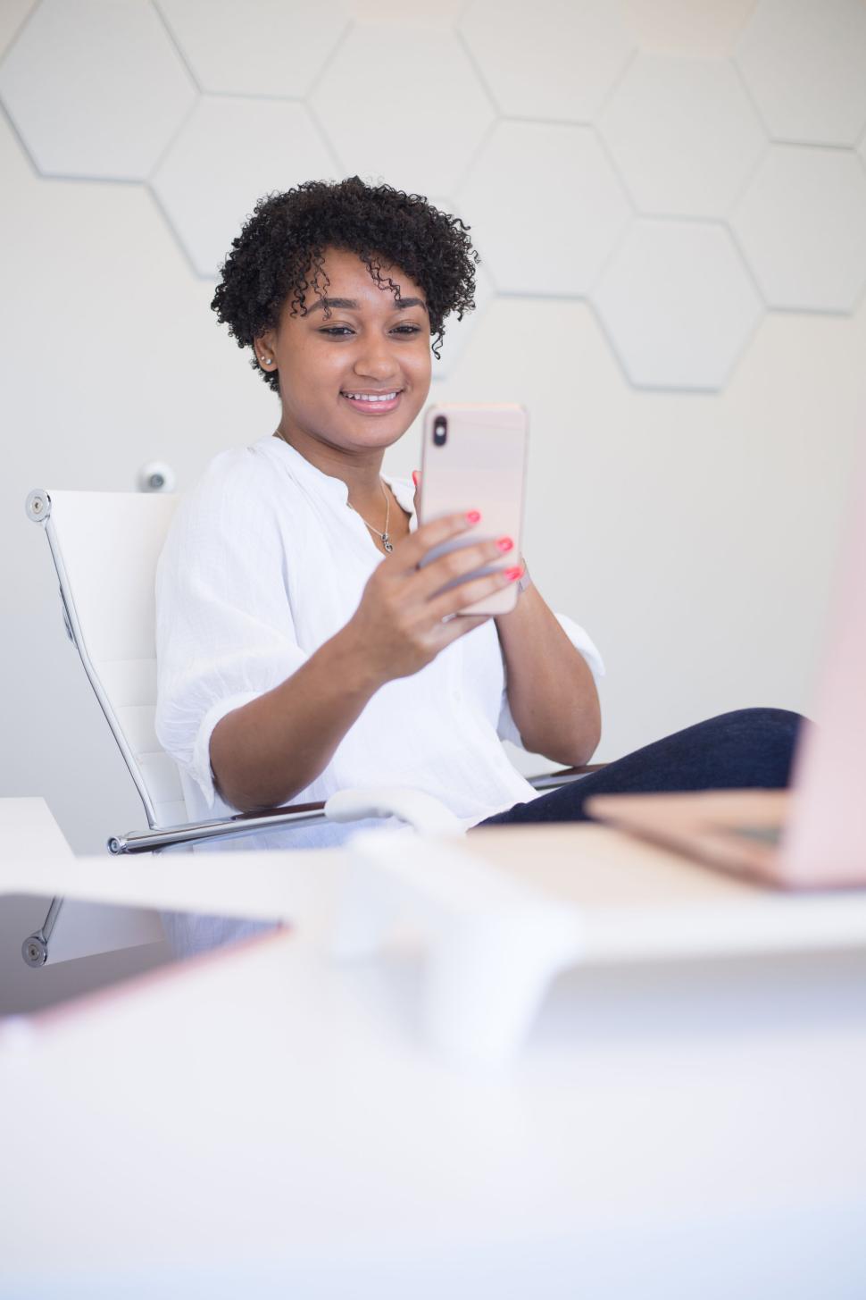 Free Image of Smiling woman in office chair using smartphone 
