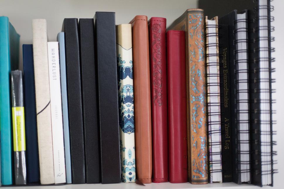 Free Image of Bookshelf with an array of books and journals arranged neatly 