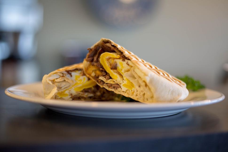 Free Image of Plate with a cut open wrap filled with eggs, vegetables, and meat 