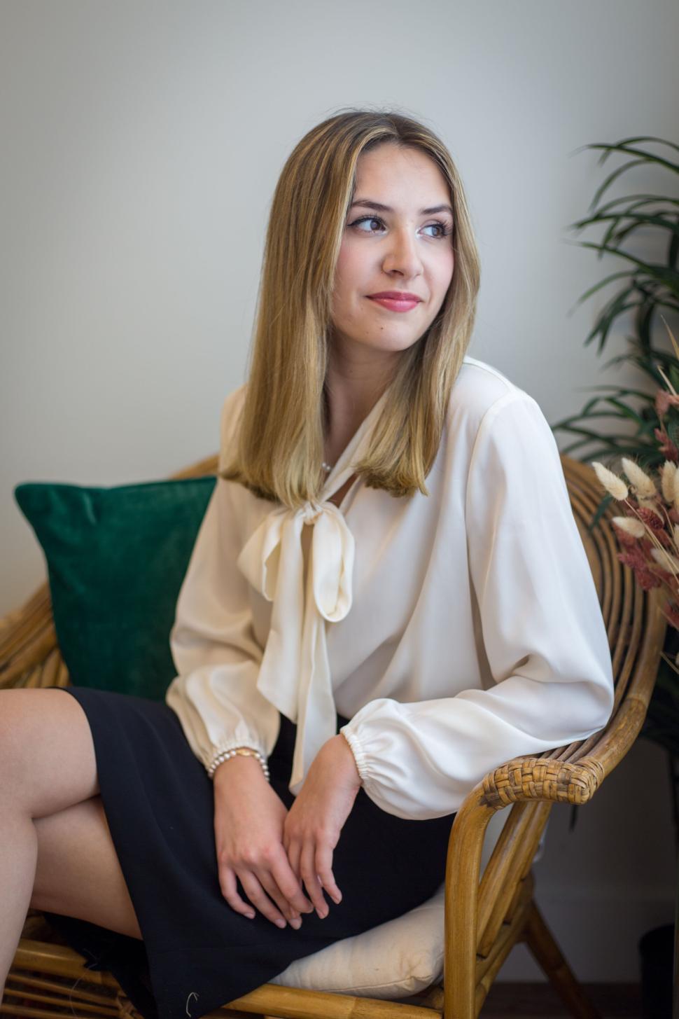 Free Image of Contemplative woman seated on a wicker chair with green pillow 