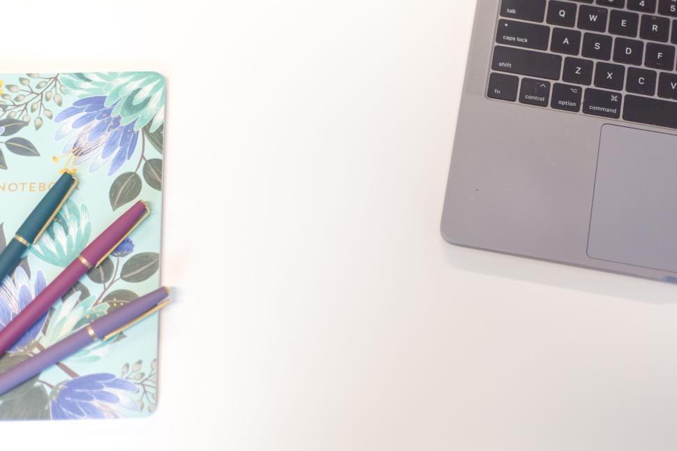 Free Image of Opened laptop, notebook, and pens arranged neatly on white desk 