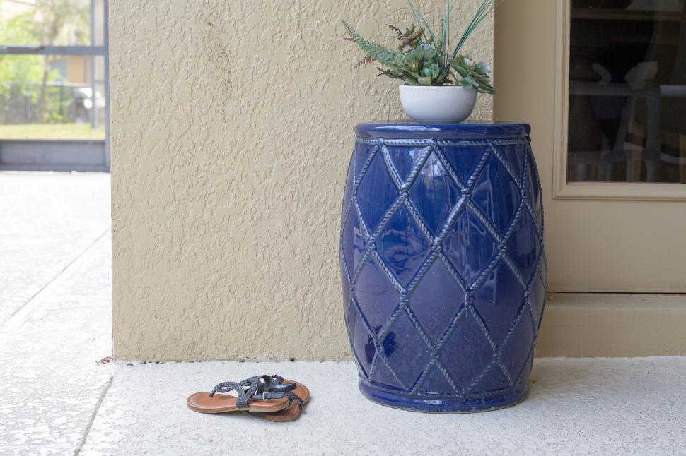 Free Image of Blue ceramic planter with succulents and sandals on the ground 