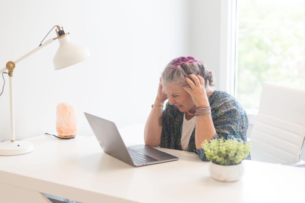 Free Image of Person sitting at desk with laptop and salt lamp, feeling stressed 