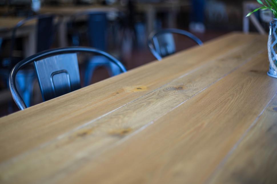 Free Image of Close view of a wooden table with metal chairs in background 