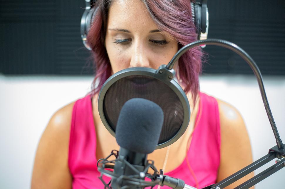 Free Image of Woman recording vocals in studio with microphone and headphones 