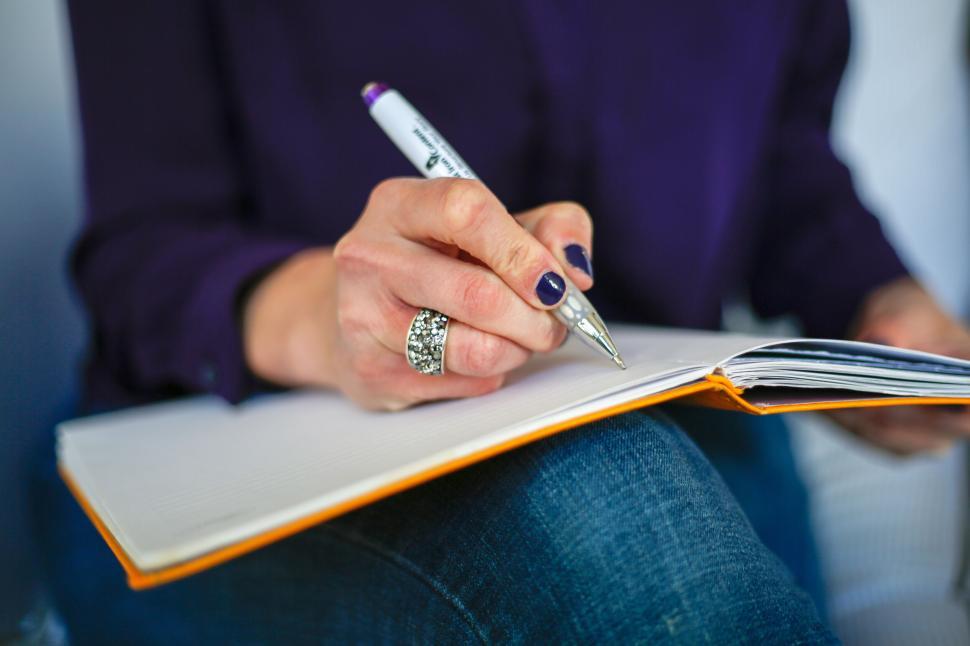 Free Image of Person Writing in Notebook with Purple Nail Polish and Ring 