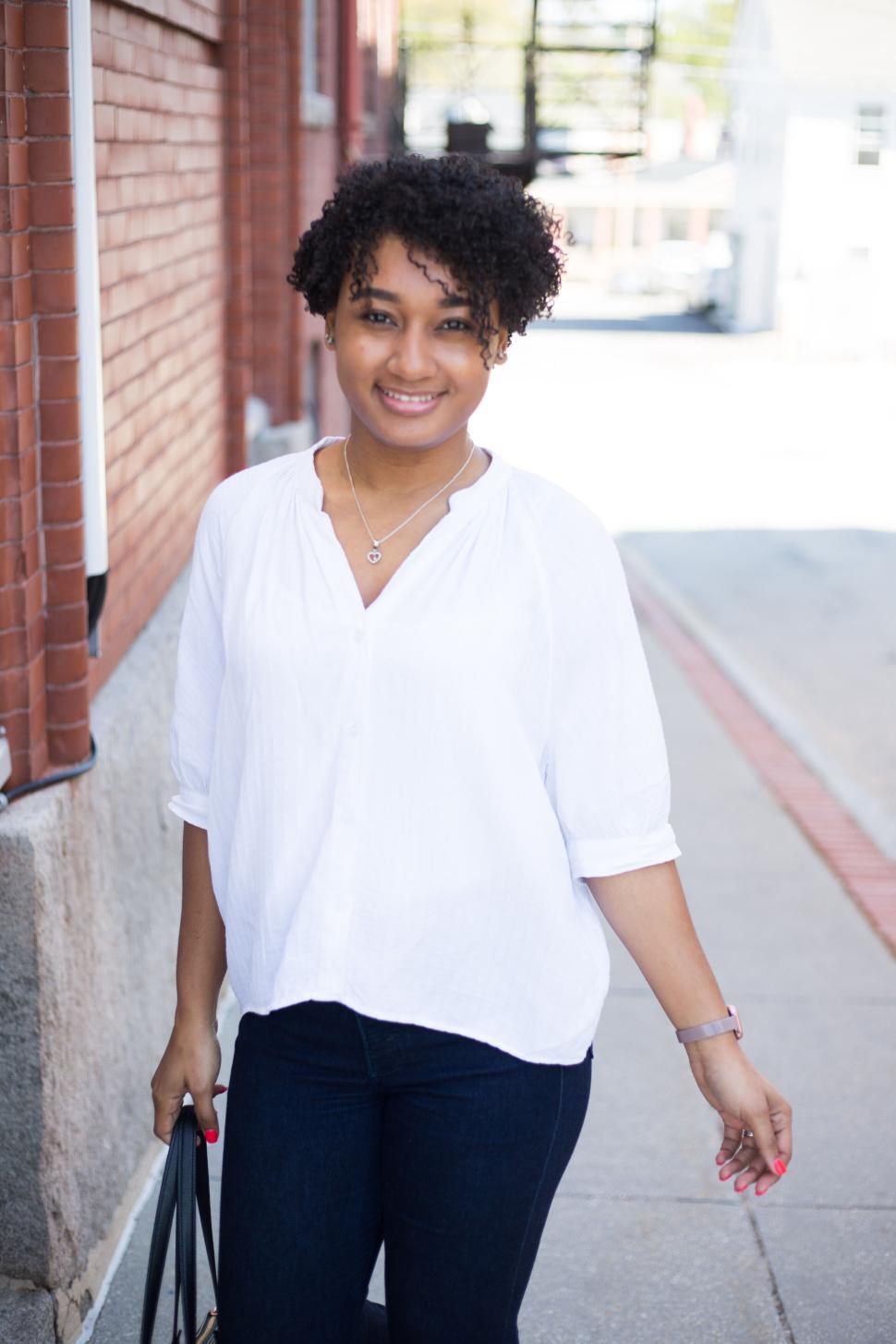 Free Image of Woman in white blouse walking along urban street in daylight 