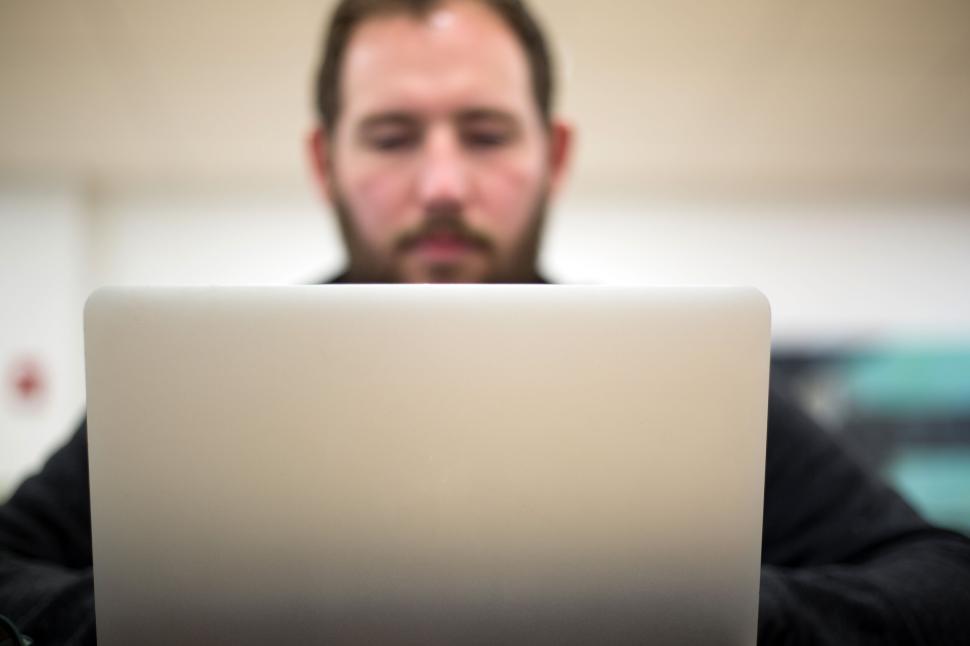 Free Image of Man working on laptop in a bright, modern office setting 