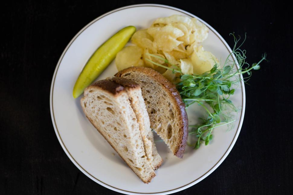 Free Image of Plate with bread, chips, pickles, and greens on a dark table 