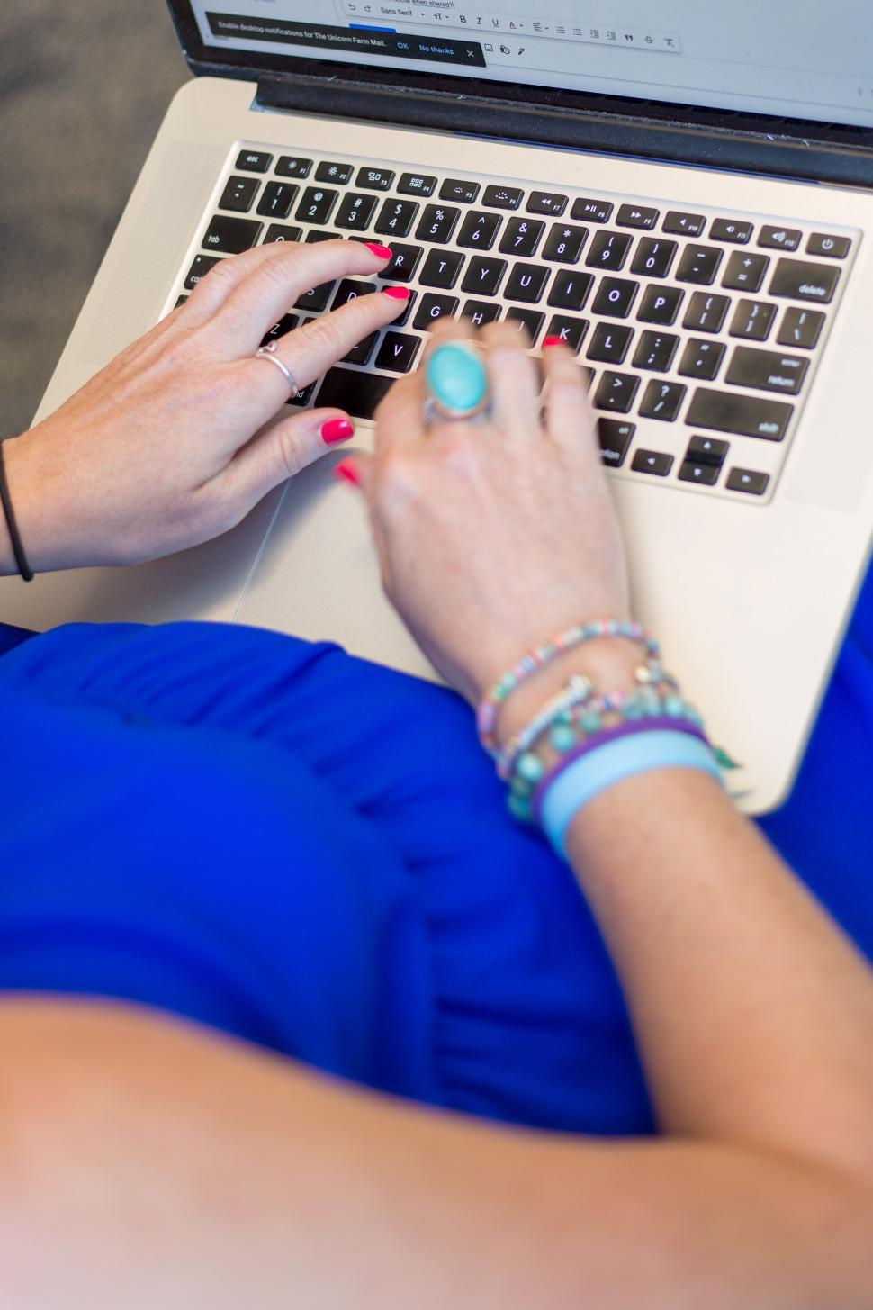 Free Image of Hands typing on laptop keyboard, accessories and jewelry visible 