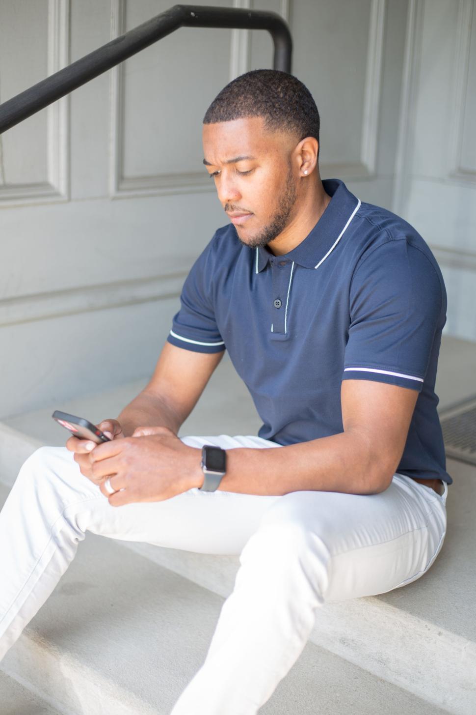 Free Image of Man sitting on stairs using smartphone in urban setting stylishly 