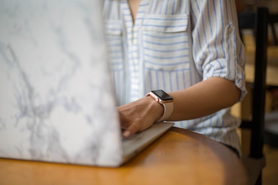Free Image of Person typing on a laptop with a striped shirt and smartwatch. 