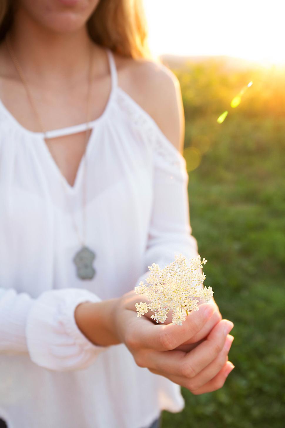 Free Image of Woman holding delicate white flowers in soft sunlight outdoors 