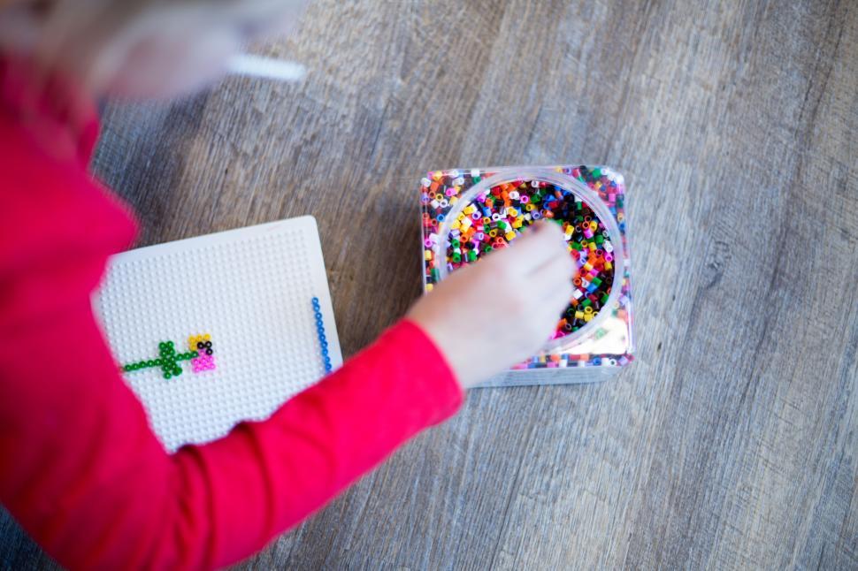 Free Image of Child playing with colorful beads for arts and crafts activity. 
