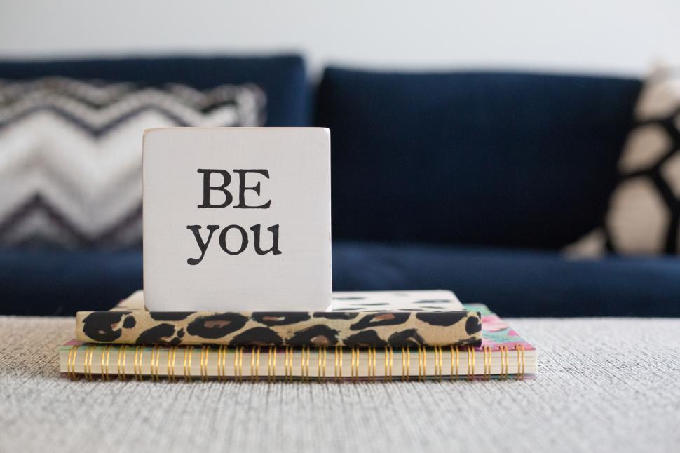 Free Image of Inspirational sign on stack of books in modern living room interior 