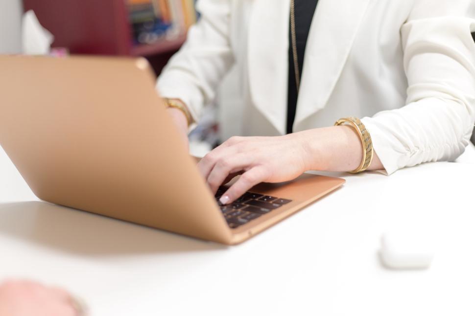 Free Image of Woman typing on laptop at neatly organized desk in office setting 
