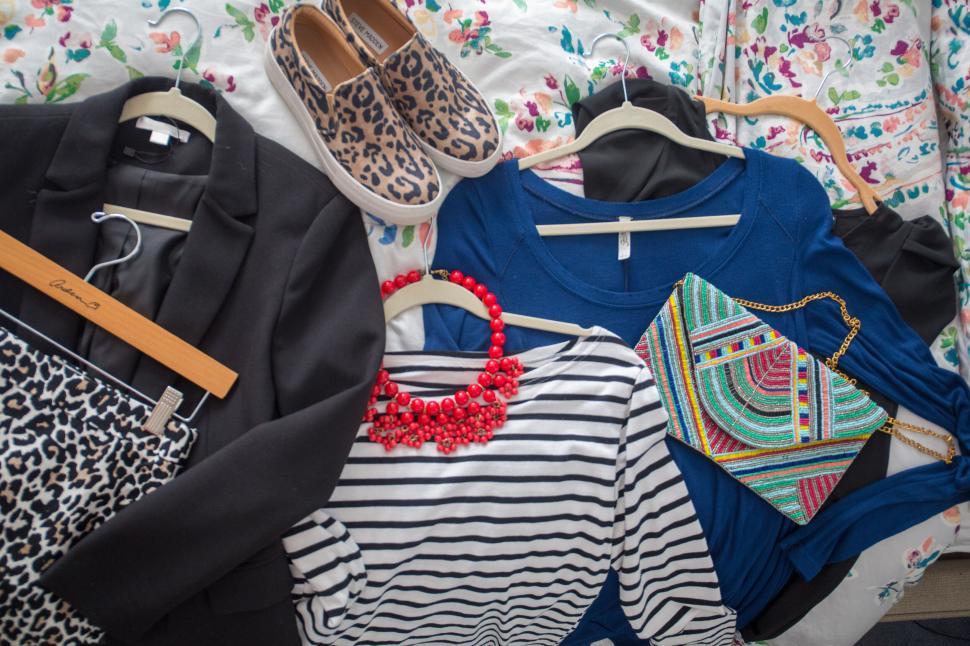 Free Image of Fashion items including shoes, clothes, and accessories on a bed. 