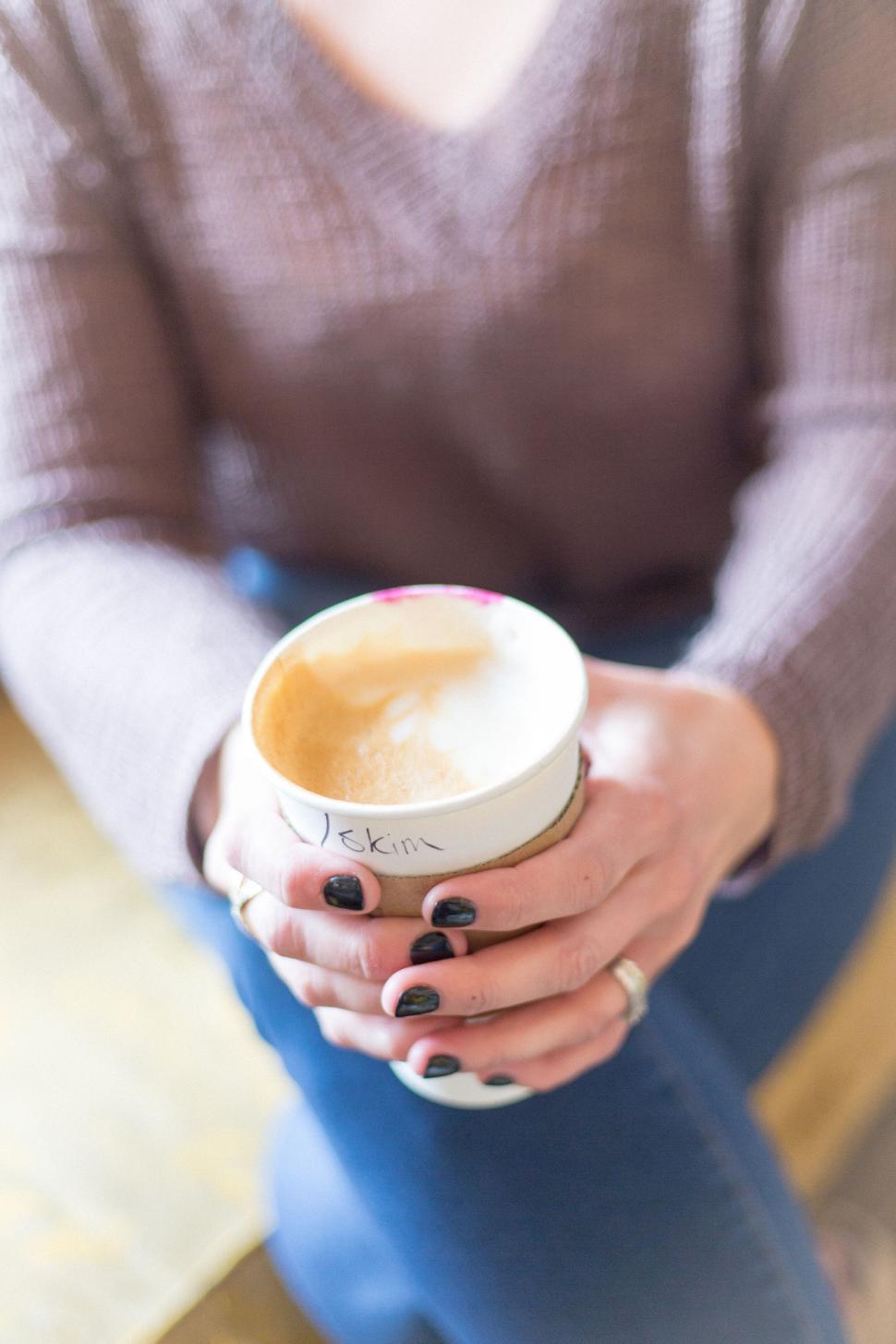 Free Image of Close-up of a person holding a coffee cup with name written on it. 