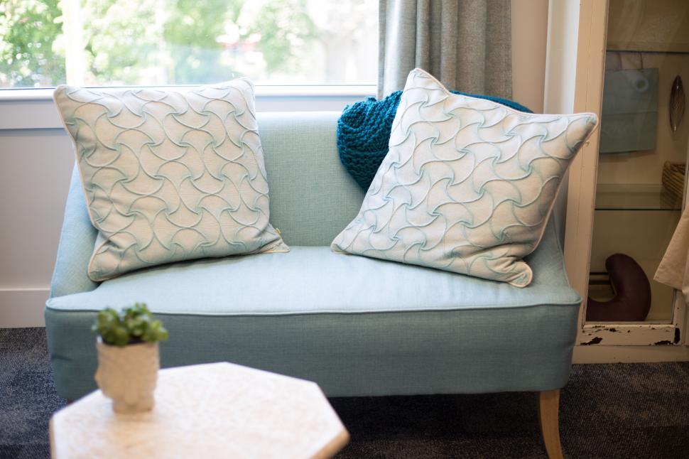 Free Image of Modern two-seater couch with pastel cushions in a sunlit room. 